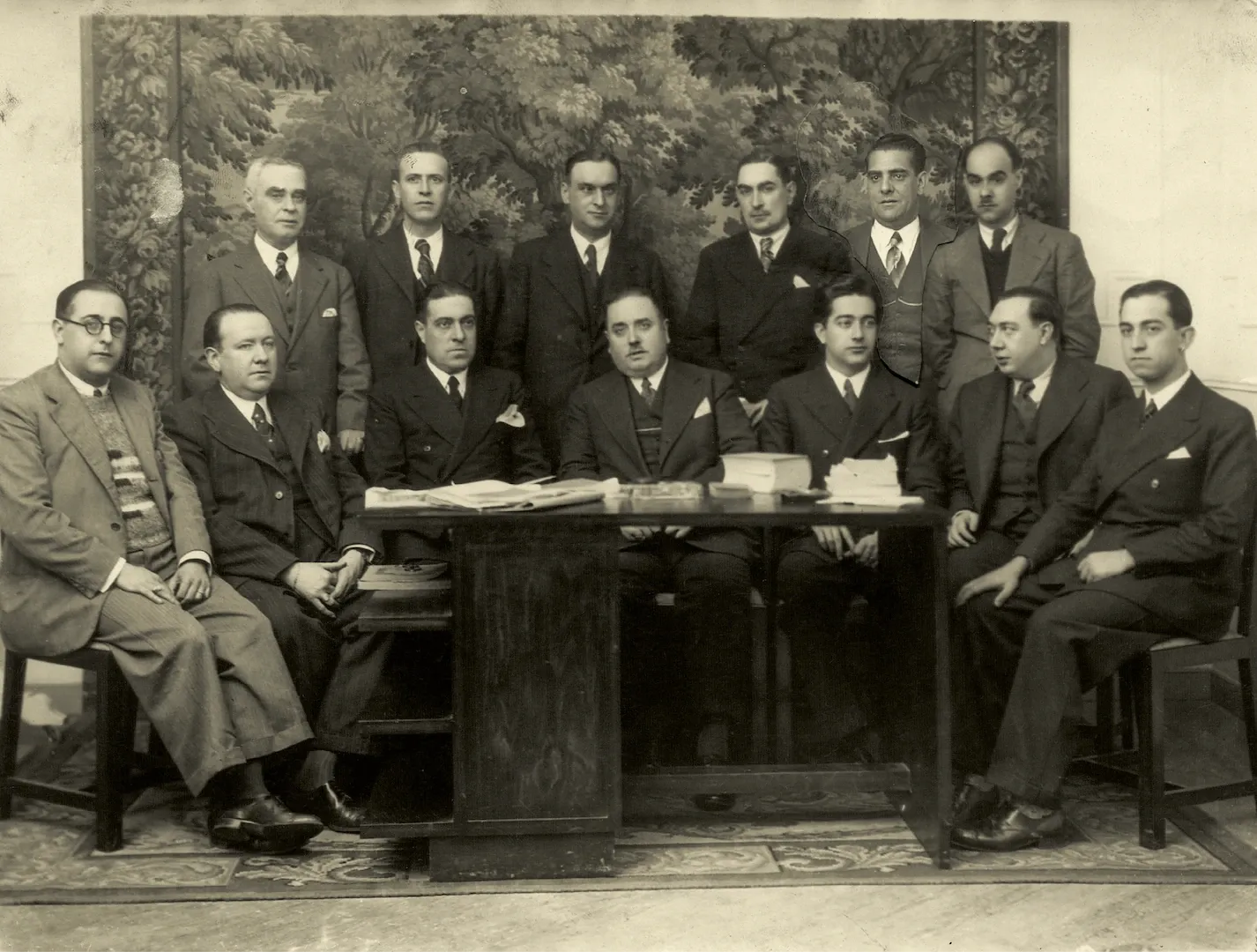 Junta Directiva de la Asociación General de Empleados del Banco de España, con el añadido del quinto personaje de pie por la izquierda procedente de otra fotografía, realizada sobre el mismo fondo vegetal, recortada y pegada sobre esta. Ca. 1936. Fotógrafo: Cristóbal Portillo Robles. Positivo. Plata en gelatina. N.º inv. 542.