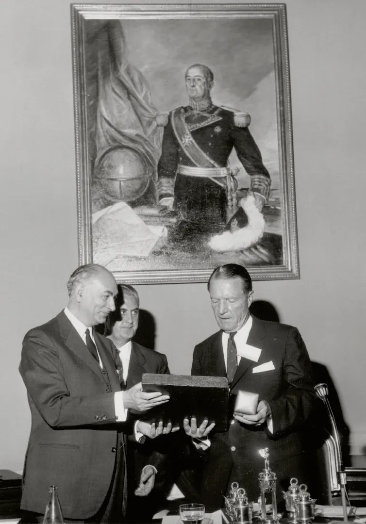 XIII Conferencia Monetaria de la American Bankers Association, celebrada en España entre el 23 y el 27 de mayo de 1966. Acto de apertura en el que el gobernador, Mariano Navarro Rubio, entrega varios regalos a George Champion, presidente de la Conferencia y del Chase Manhattan Bank. 24 de mayo de 1966. Fotógrafo: Manuel Aumente Menéndez. Positivo. Plata en gelatina. N.º inv. 4681.