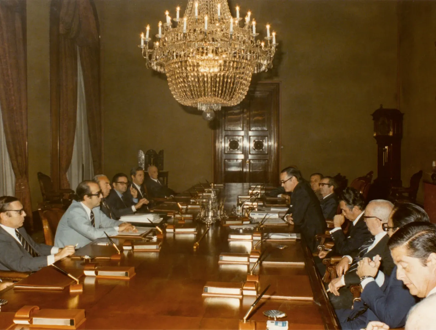 Reunión del Consejo de Gobierno del Banco de España. A la derecha, entre otros, Alfonso Escámez, consejero; José M.ª Latorre, subgobernador 1.º; José M.ª López de Letona, gobernador, y los consejeros José Valenzuela Soler, Enrique Fuentes Quintana y Miguel Primo de Rivera. A la izquierda, entre otros, Luis Ángel Rojo, Ángel Madroñero y Antonio Sánchez-Pedreño, directores generales. 1977. Fotógrafo: desconocido. Positivo. Copia cromógena. N.º inv. 5036.