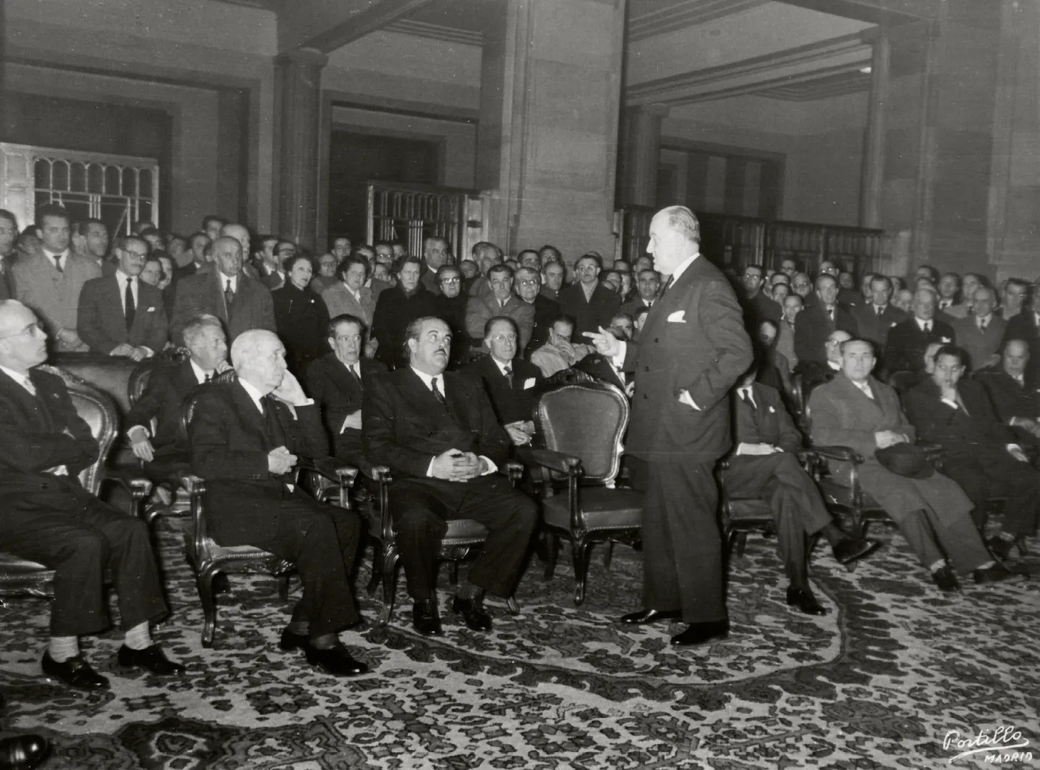 Acto de celebración del centenario de la Caja de Pensiones del Banco de España. Discurso de Fernando Suárez de Tangil, ministro de Obras Públicas y consejero del Banco de España en el patio de Operaciones. 18 de febrero de 1953. Fotógrafo: Cristóbal Portillo Robles. Positivo. Plata en gelatina. N.º inv. 5364.