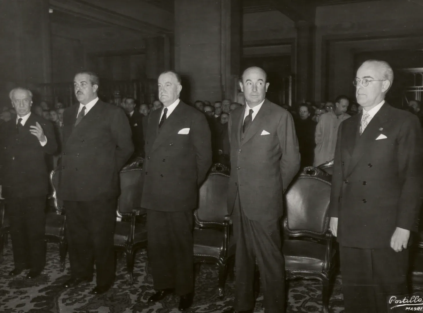 Acto de celebración del centenario de la Caja de Pensiones del Banco de España. De izquierda a derecha, Joaquín Benjumea, gobernador del Banco de España; José Antonio Girón, ministro de Trabajo; Fernando Suárez de Tangil; Manuel Arburúa, ministro de Comercio, y Luis Sáez de Ibarra, subgobernador del Banco de España. 18 de febrero de 1953. Fotógrafo: Cristóbal Portillo Robles. Positivo. Plata en gelatina. N.º inv. 5373.