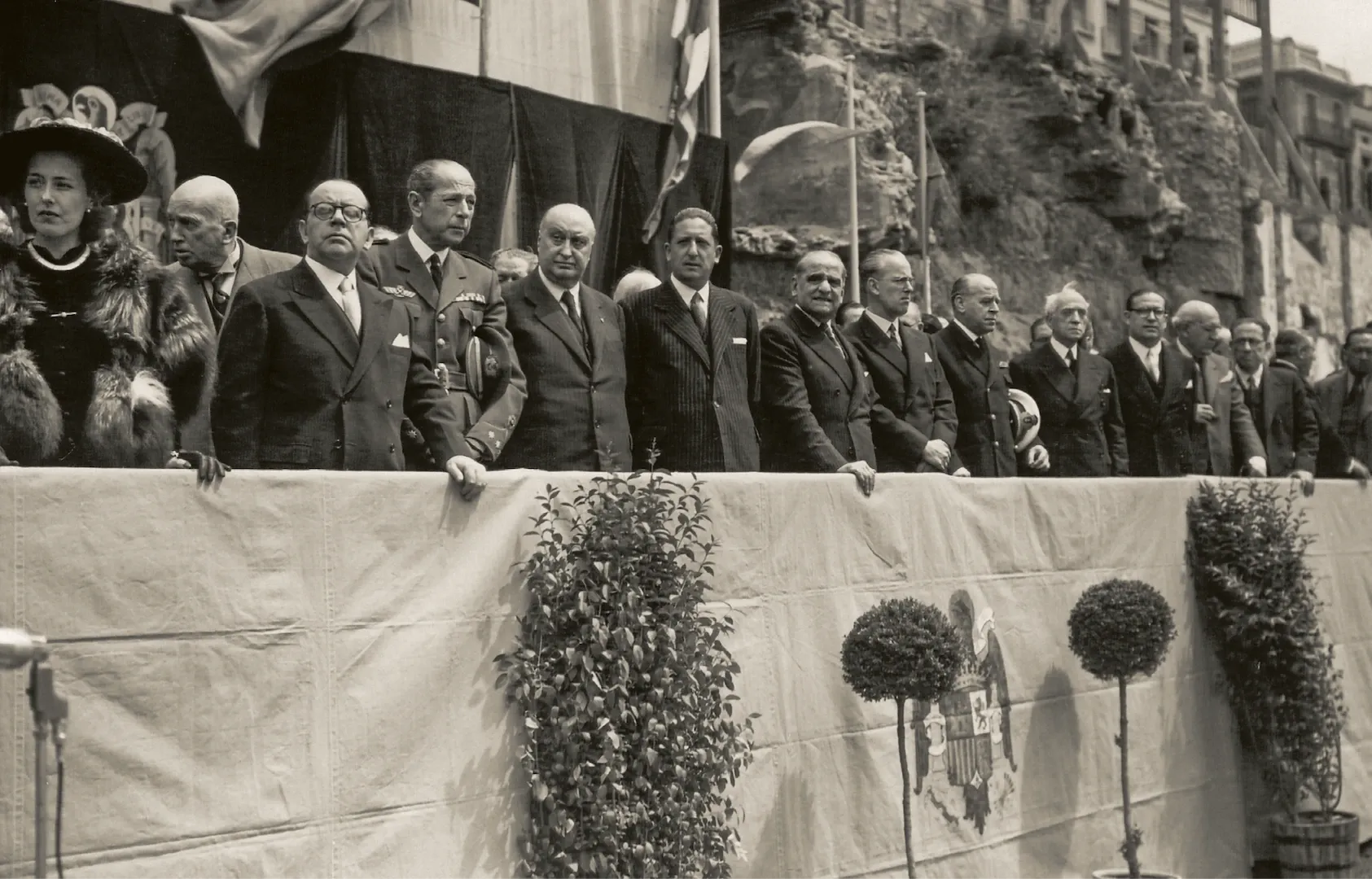 Sucursal de Barcelona. Tribuna de invitados a la ceremonia de colocación de la primera piedra del edificio de la plaza de Cataluña, con presencia de Antonio Goicoechea, gobernador, Luis Sáez de Ibarra, subgobernador, y autoridades civiles y militares de Cataluña. 1948. Fotógrafo: desconocido. Positivo. Plata en gelatina. N.º inv. 16393.