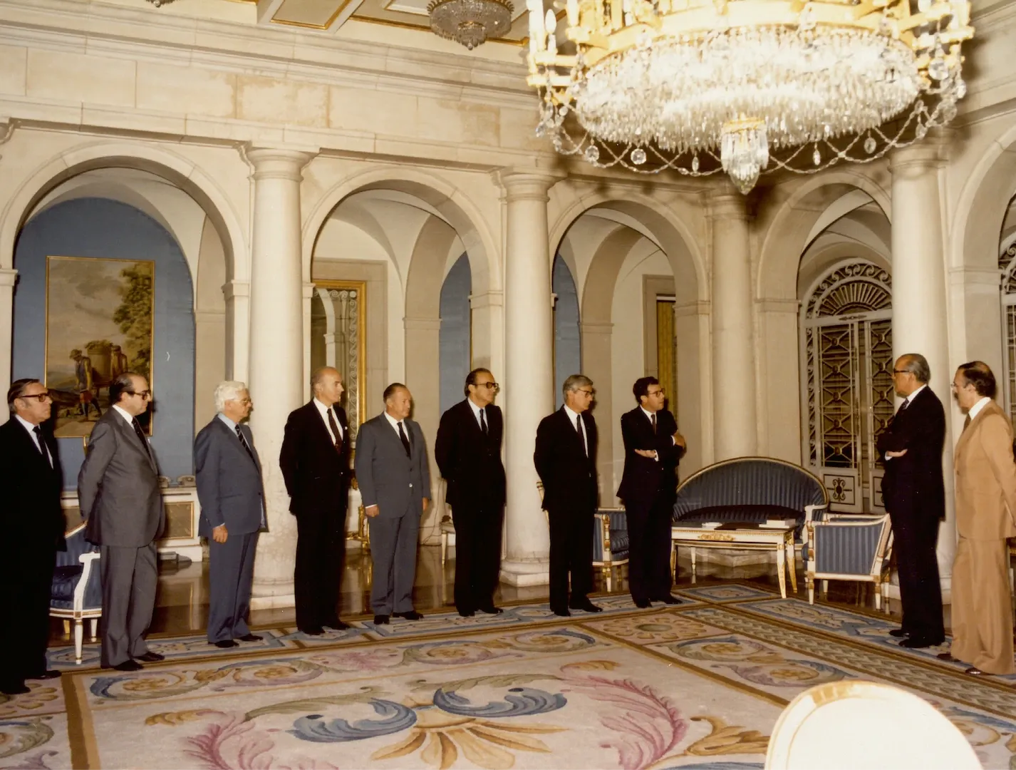 Visita del Consejo Ejecutivo del Banco de España al presidente de Gobierno en el palacio de La Moncloa. De izquierda a derecha, Antonio Sánchez-Pedreño, Ángel Madroñero y Juan Caldés Lizana, directores generales; Gonzalo Anes, Manuel Varela Parache y Enrique Fuentes Quintana, consejeros; Mariano Rubio, subgobernador; José Ramón Álvarez Rendueles, gobernador; Leopoldo Calvo-Sotelo, presidente del Gobierno, y Juan Antonio García Díez, vicepresidente del Gobierno para Asuntos Económicos. 21 de julio de 1982. Fotógrafo: Lumifot. Positivo. Copia cromógena.